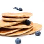 A stack of protein pancakes topped with a small amount of yogurt and a few blueberries.