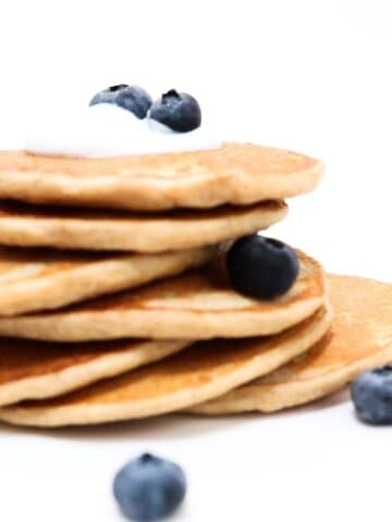 A stack of protein pancakes topped with a small amount of yogurt and a few blueberries.