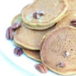 A plate of pumpkin pancakes topped with toasted pecans.