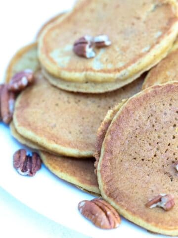 A plate of pumpkin pancakes topped with toasted pecans.