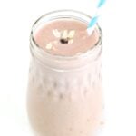 One Peanut Butter Banana Oatmeal Smoothie in a glass jar topped with oats and a mini chocolate chip, served with a straw.