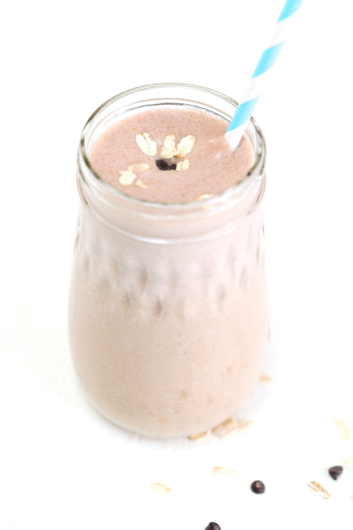 One peanut butter banana oatmeal smoothie in a glass jar with a blue and white striped straw.