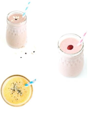 Three different smoothies in glass jars with striped straws.