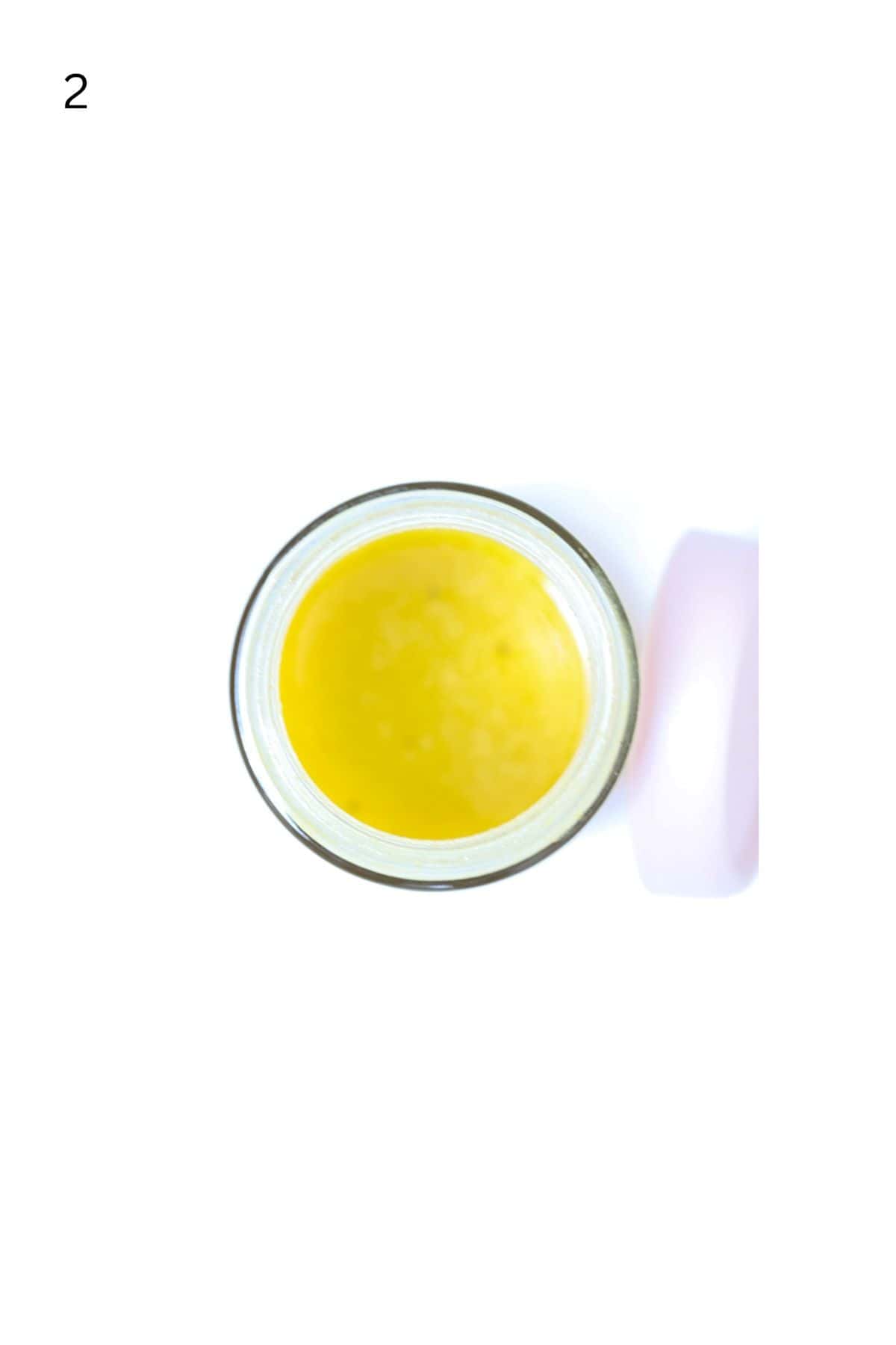 Top view of apple cider vinaigrette salad dressing in a jar with the lid to the side.