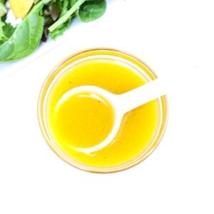 Apple Cider Vinaigrette Dressing in a small glass bowl with a white serving spoon.