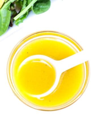 Apple Cider Vinaigrette Dressing in a small glass bowl with a white serving spoon.