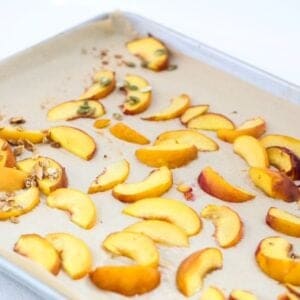 Roasted peach slices on a lined baking sheet.