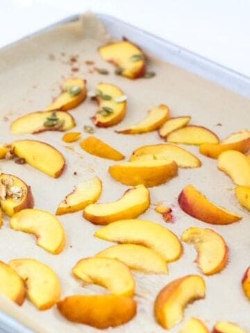 Roasted peach slices on a lined baking sheet.