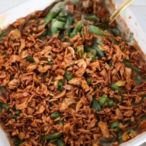 Green Bean Casserole in a white, square baking dish with a serving spoon.