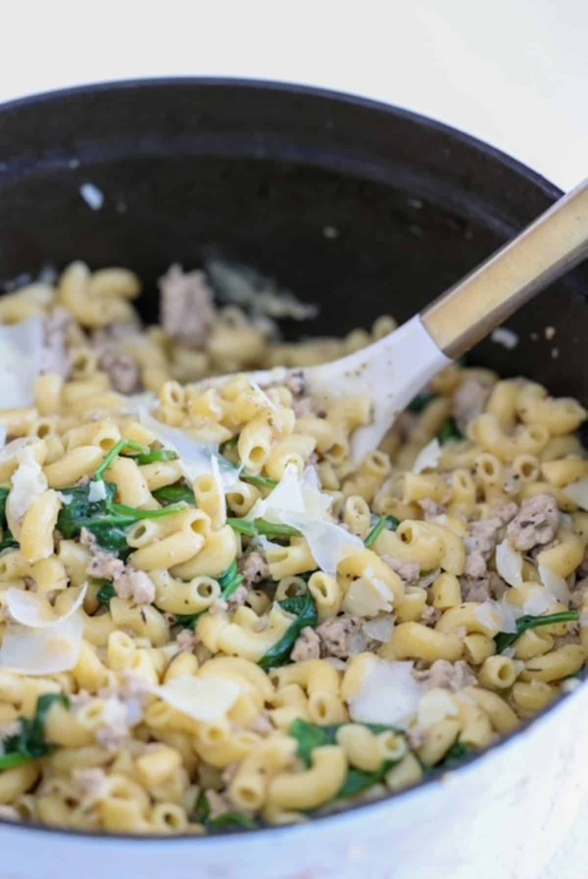 Ground Turkey and Pasta dish in a white Staub Dutch oven with a white and gold serving spoon.