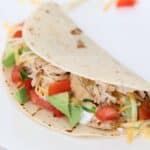 One chicken taco on a white plate.