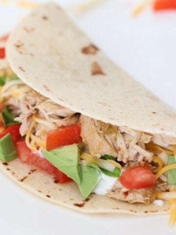 One chicken taco on a white plate.