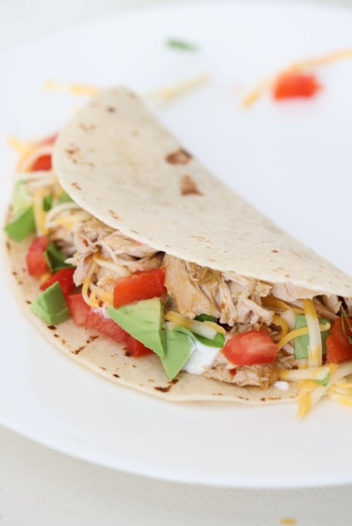 One chicken taco served in a flour tortilla with toppings.