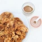 Seasoned chicken on a white plate with chicken seasoning in a n open jar to the side.
