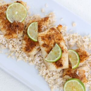 Air-fried cod topped with seasoning and slices of fresh lime on a white dish.