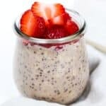 Chocolate overnight oats in a glass jar topped with strawberries.