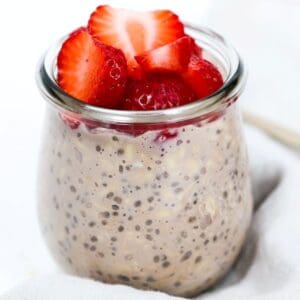 Chocolate overnight oats in a glass jar topped with strawberries.