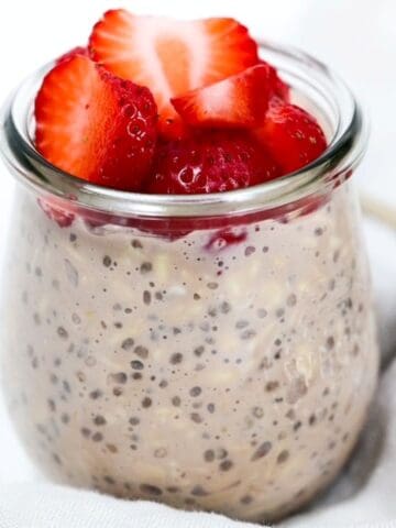 Chocolate overnight oats in a glass jar topped with strawberries.
