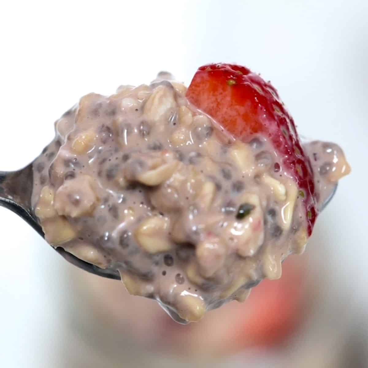One spoonful of chocolate overnight oats on a spoon with a strawberry slice.