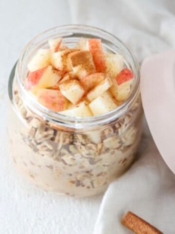 Apple cinnamon overnight oats in a glass jar with the lid to the side.
