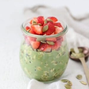 Matcha Overnight Oats in a glass jar topped with fresh strawberries.