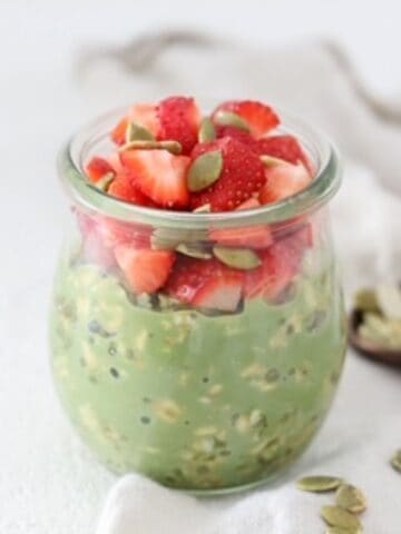 Matcha Overnight Oats in a glass jar topped with fresh strawberries.