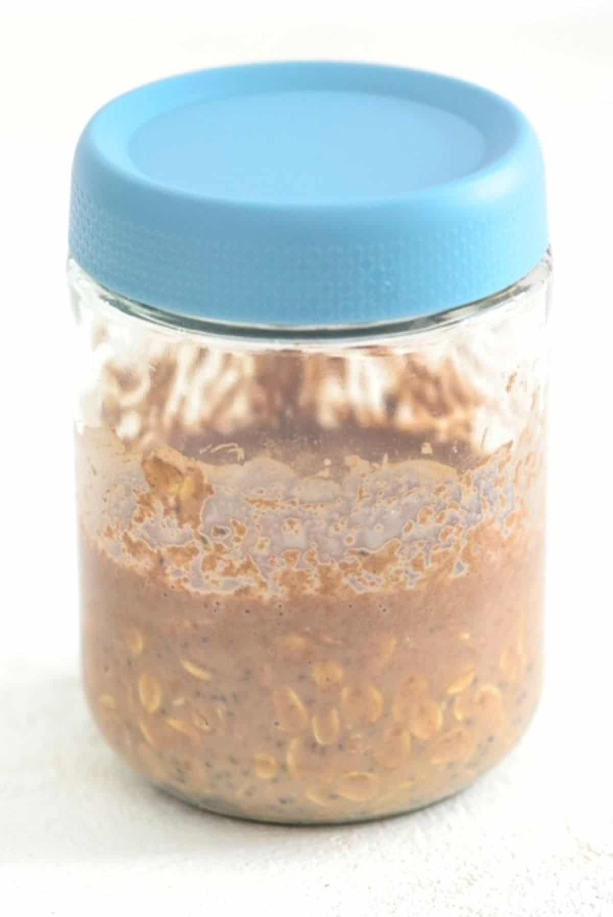Ingredients for making chocolate peanut butter overnight oats in a jar with a lid on it.