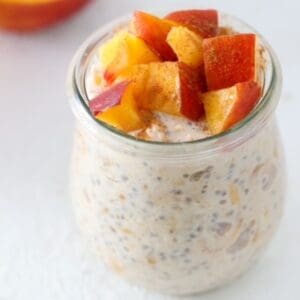 Peaches and Cream Overnight Oats in a tulp style glass jar.