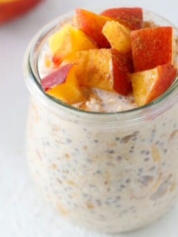 Peaches and Cream Overnight Oats in a tulp style glass jar.