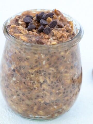 Chocolate peanut butter overnight oats topped with mini chocolate chips in a glass jar.