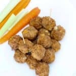 Buffalo Chicken Meatballs on a plate with carrot and celery sticks.