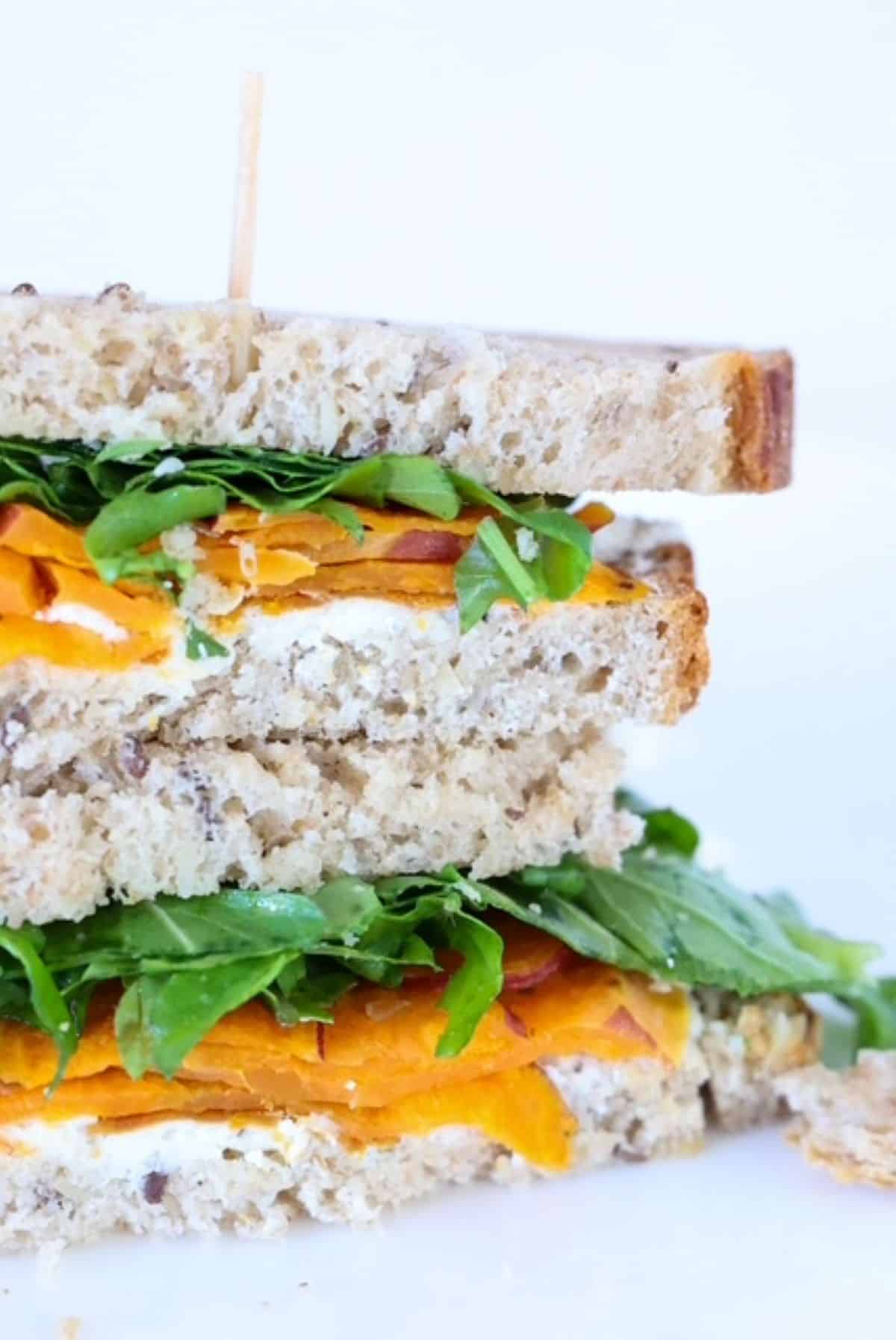 Two halves of a goat cheese sandwich with veggies, stacked.